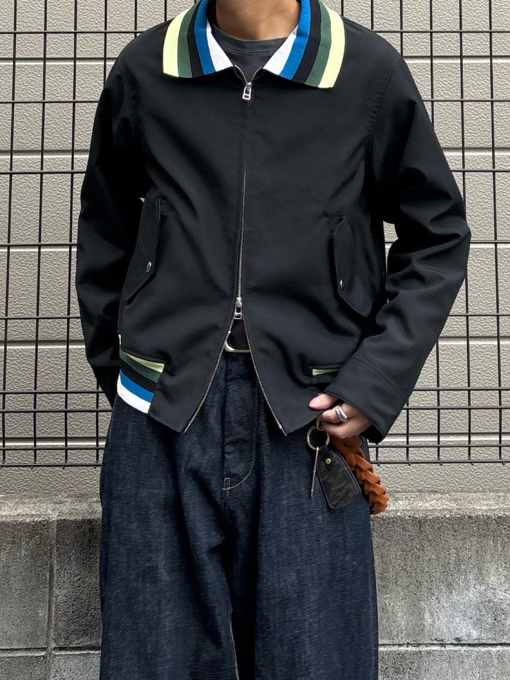 ブラック系のブルゾン、ブルー系のデニムパンツ、ブラウン系のサンダルを着用したメンズの春コーディネートの3枚目の写真