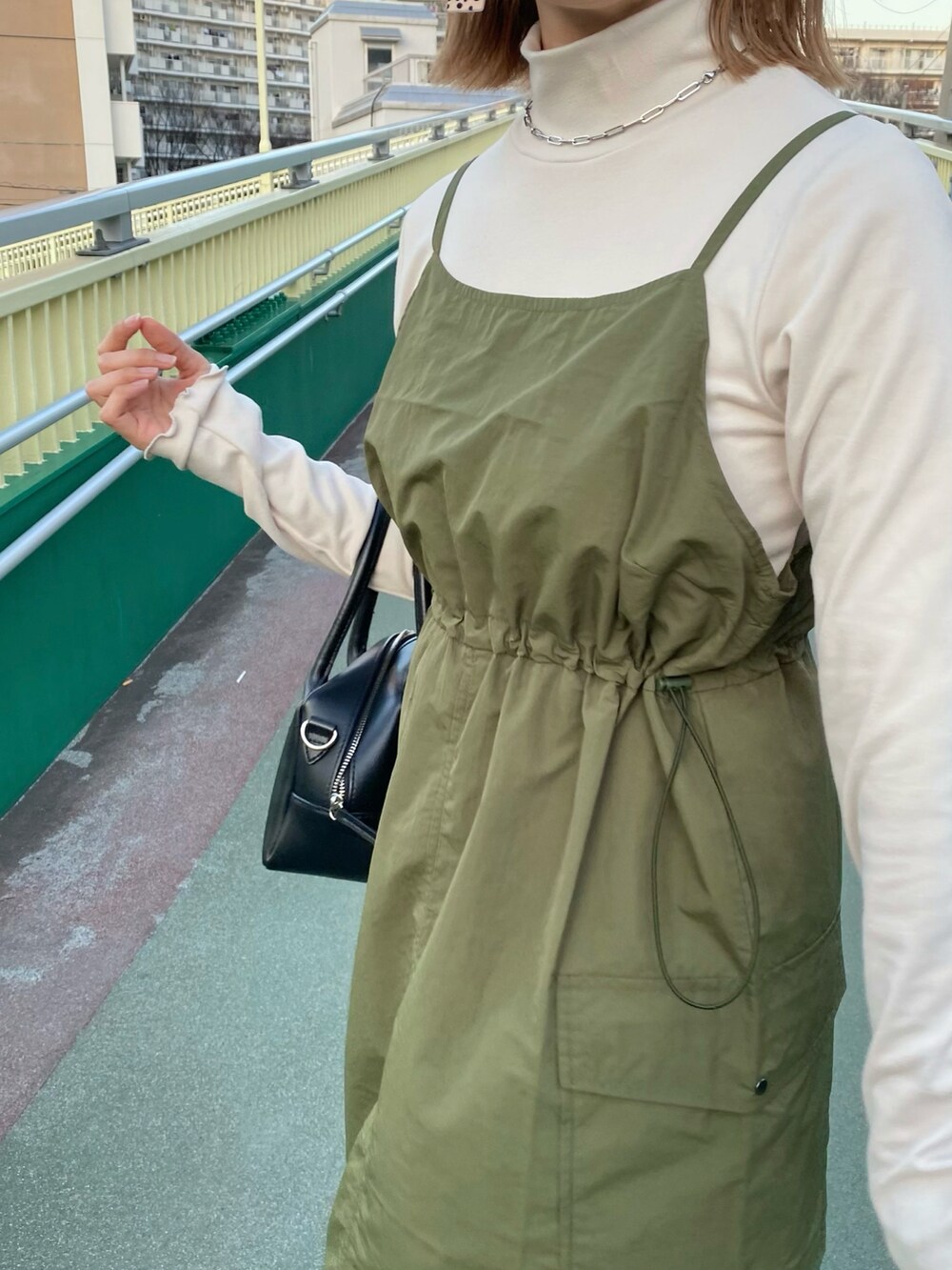 ブラック系のバッグ、グリーン系のワンピース、ホワイト系のスニーカーを着用したレディースの春コーディネートの4枚目の写真