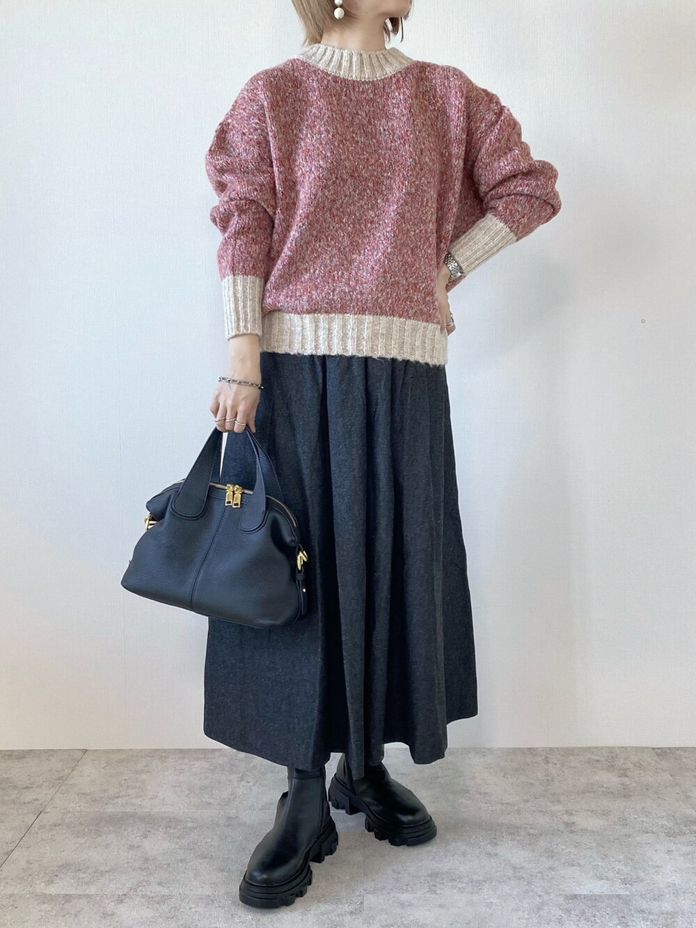ピンク系のニット/セーター、ブラック系のバッグ、ブラック系のスカートを着用したレディースの秋コーディネートの2枚目の写真