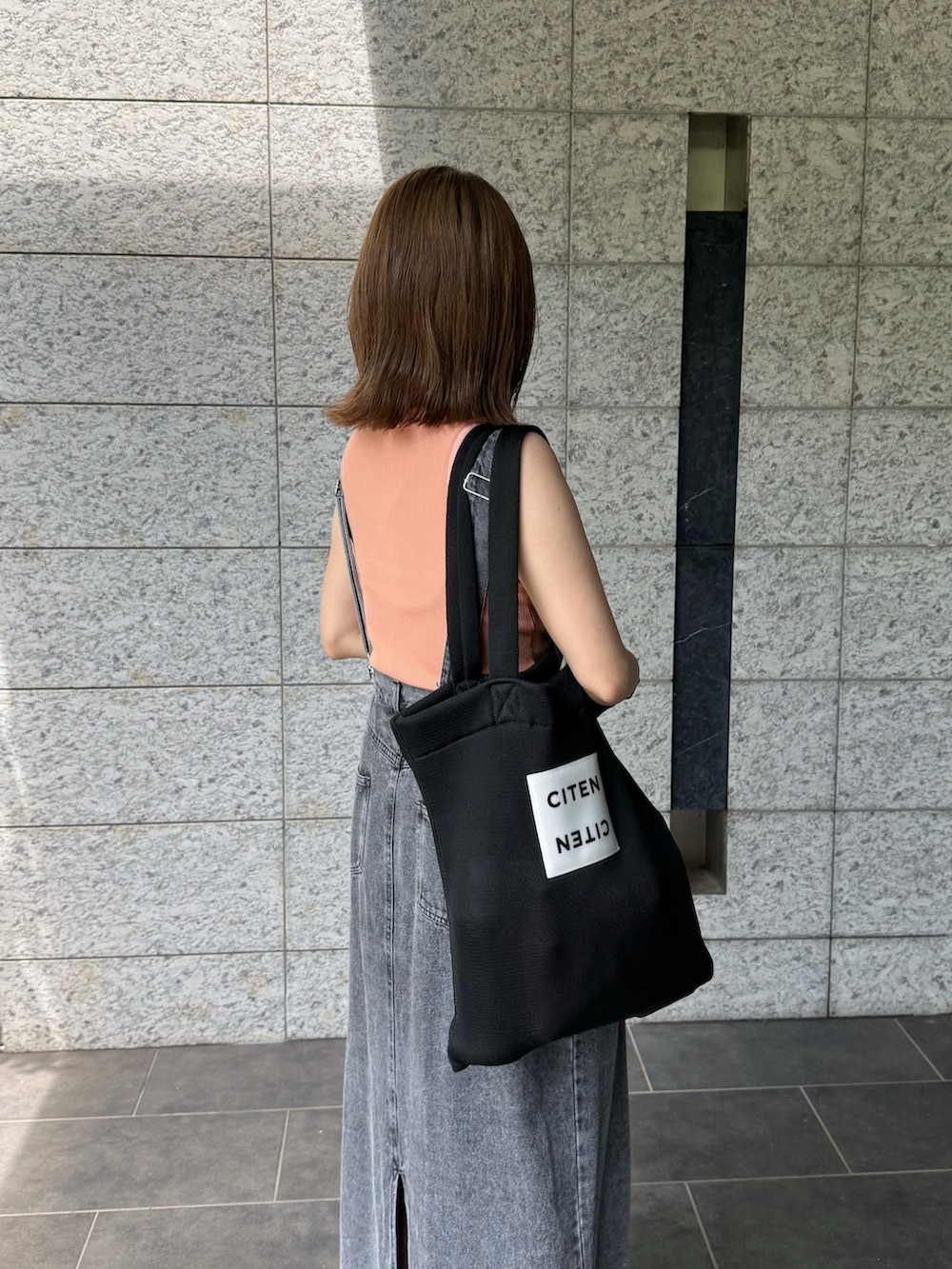 ブラック系のサンダル、ピンク系のTシャツ/カットソー、ブラック系のジャンパースカートを着用したレディースの夏コーディネートの4枚目の写真
