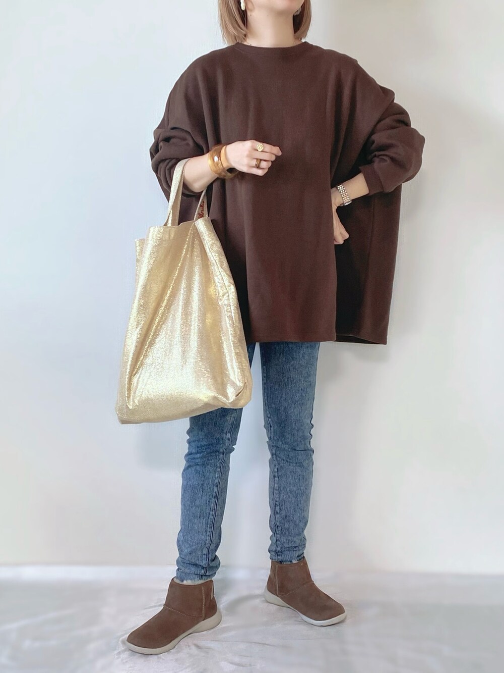 ブラウン系のブーツ、ゴールド系のトートバッグ、ブラウン系のスウェットを着用したレディースの冬コーディネートの3枚目の写真