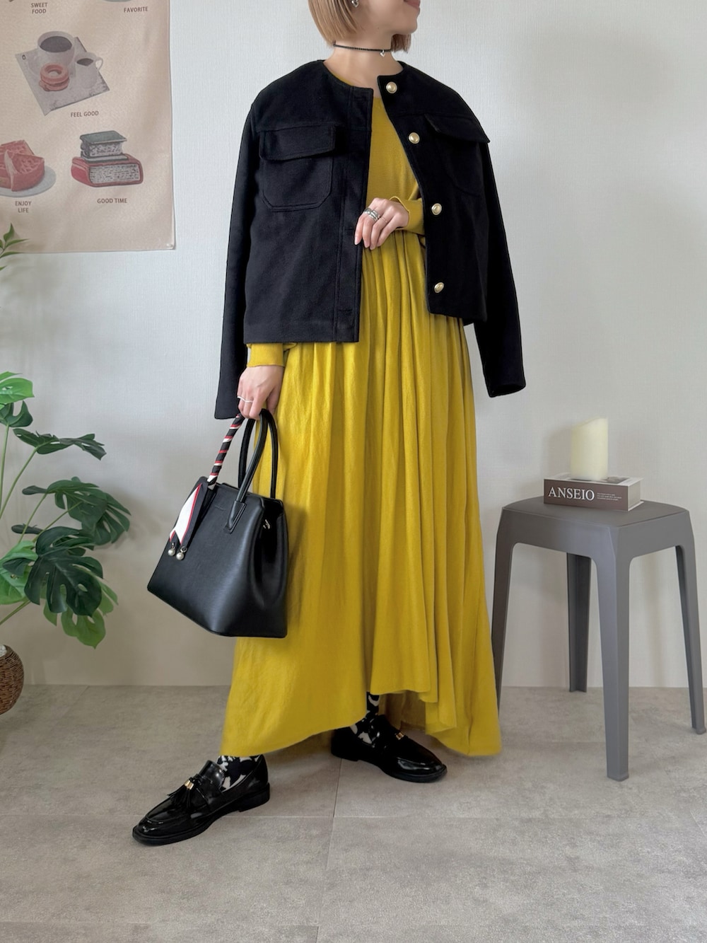 ブラック系のジャケット/アウター、ブラック系のハンドバッグ、イエロー系のワンピースを着用したレディースの冬コーディネートの3枚目の写真