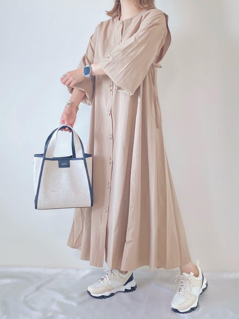 ベージュ系のシャツワンピース、ブラック系のバッグ、ホワイト系のスニーカーを着用したレディースの夏コーディネートの2枚目の写真