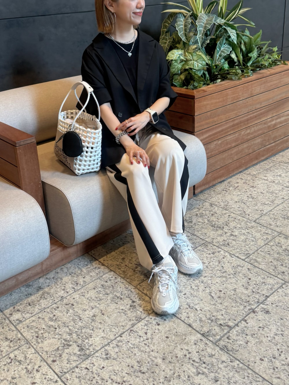 ホワイト系のスニーカー、ホワイト系のかごバッグ、ブラック系のジャケット/アウターを着用したレディースの夏コーディネートの4枚目の写真