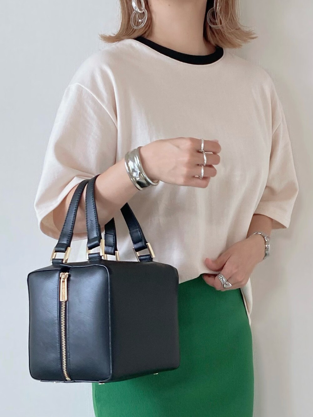 ブラック系のハンドバッグ、ベージュ系のTシャツ/カットソー、グリーン系のスカートを着用したレディースの秋コーディネートの3枚目の写真