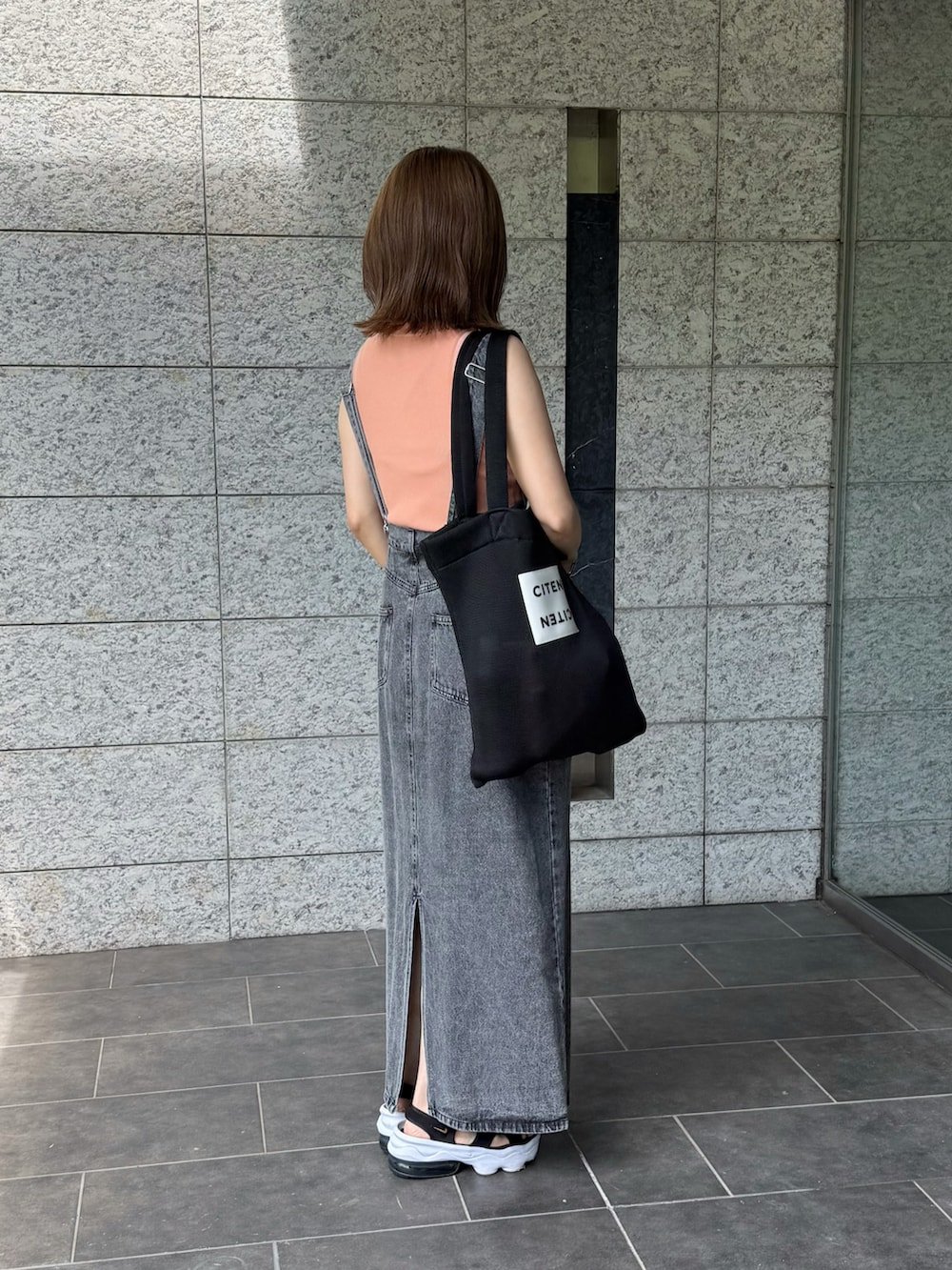 ブラック系のサンダル、ピンク系のTシャツ/カットソー、ブラック系のジャンパースカートを着用したレディースの夏コーディネートの2枚目の写真