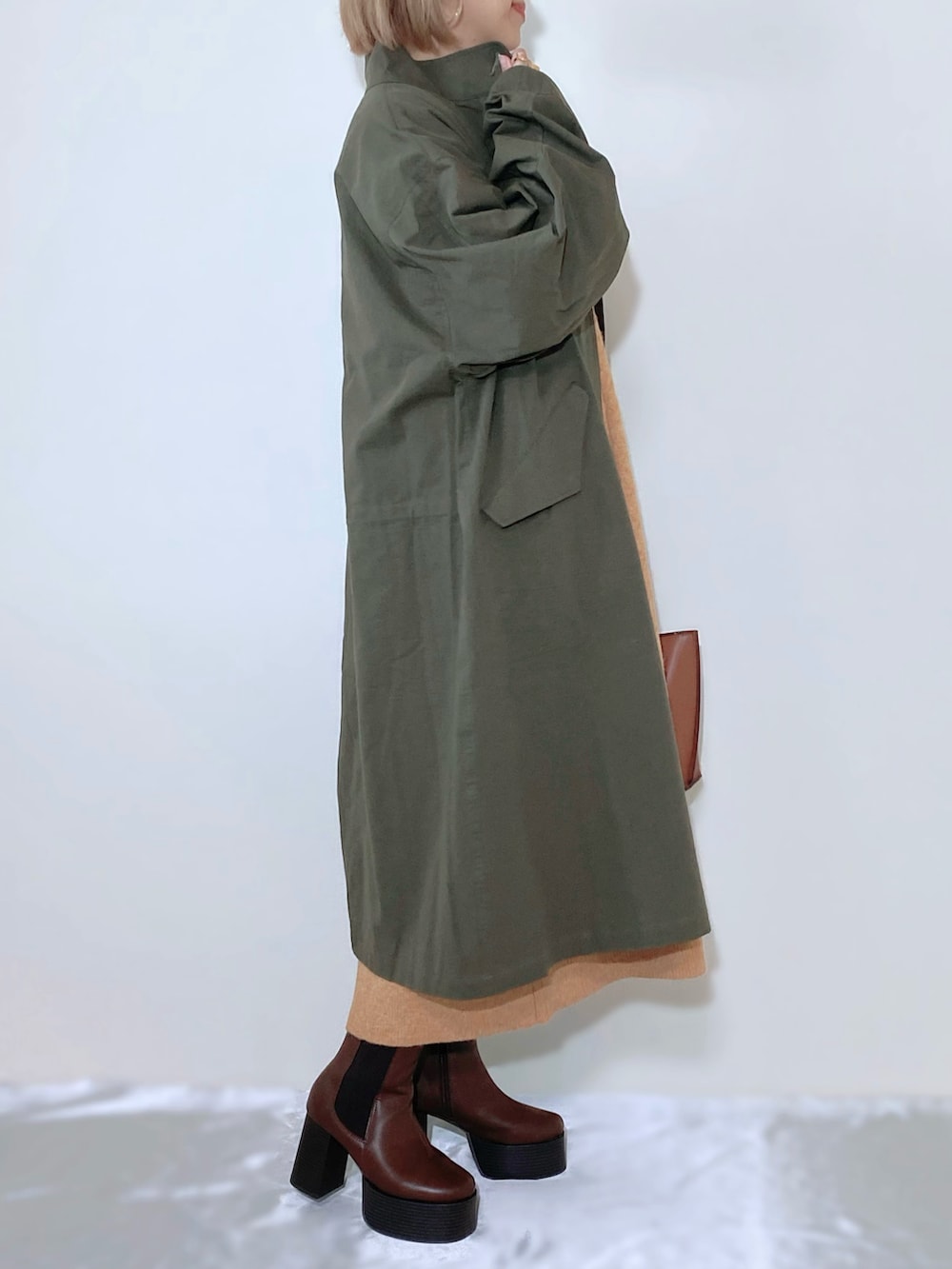 オレンジ系のワンピース、ブラウン系のバッグ、ブラウン系のブーツを着用したレディースの秋コーディネートの4枚目の写真