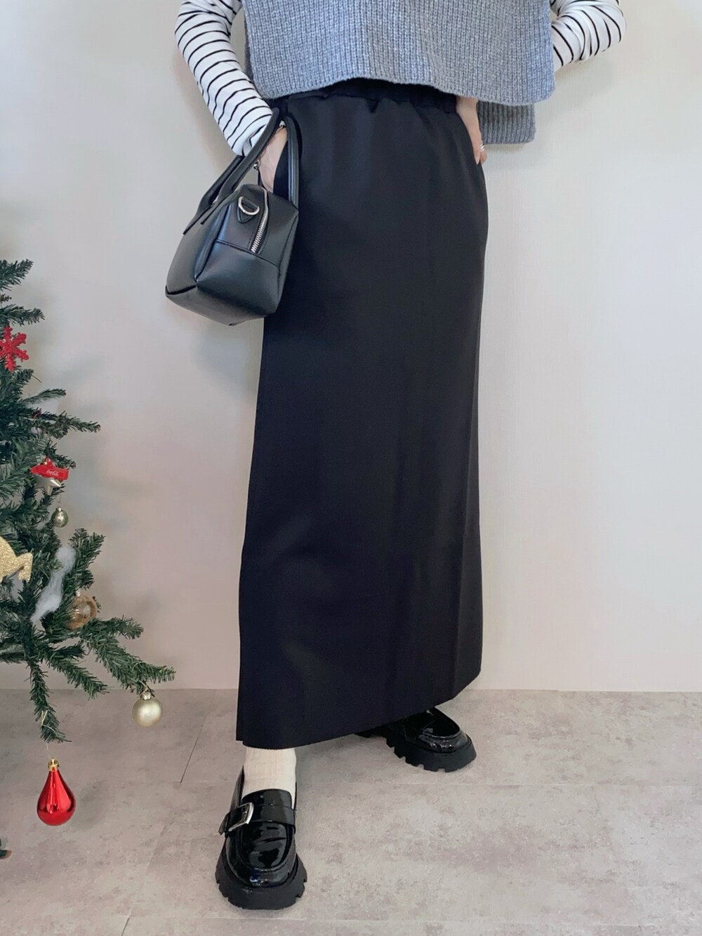 グレー系のベスト、ホワイト系のTシャツ/カットソー、ブラック系のスカートを着用したレディースの冬コーディネートの4枚目の写真