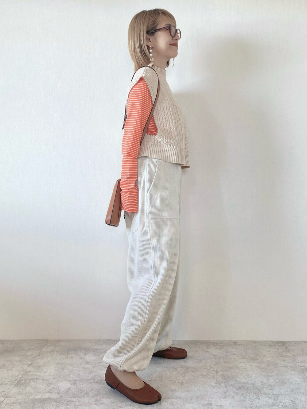 オレンジ系のTシャツ/カットソー、ベージュ系のその他パンツ、ホワイト系のベストを着用したレディースの秋コーディネートの3枚目の写真