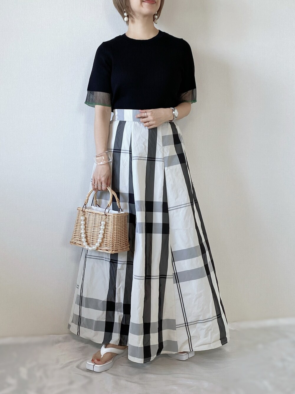 ブラック系のニット/セーター、ホワイト系のスカート、ベージュ系のかごバッグを着用したレディースの夏コーディネートの3枚目の写真