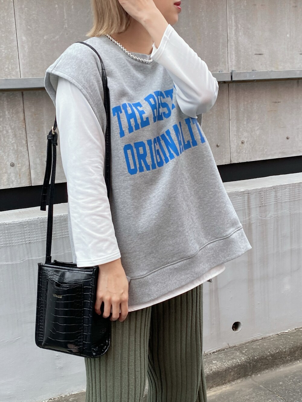 グレー系のベスト、ホワイト系のTシャツ/カットソー、ブラック系のバッグを着用したレディースの冬コーディネートの4枚目の写真