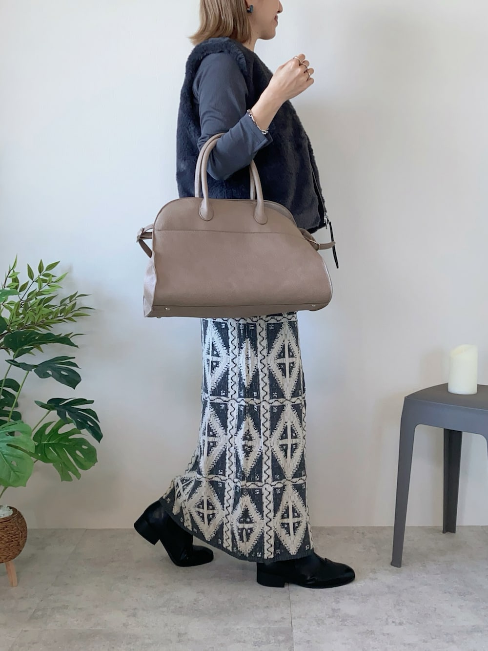 グレー系のベスト、ベージュ系のボストンバッグ、グレー系のスカートを着用したレディースの秋コーディネートの3枚目の写真