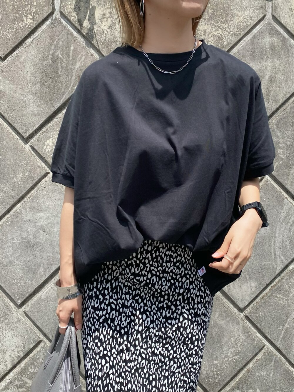 ブラック系のスカート、ブラック系のパンプス、グレー系のハンドバッグを着用したレディースの夏コーディネートの4枚目の写真