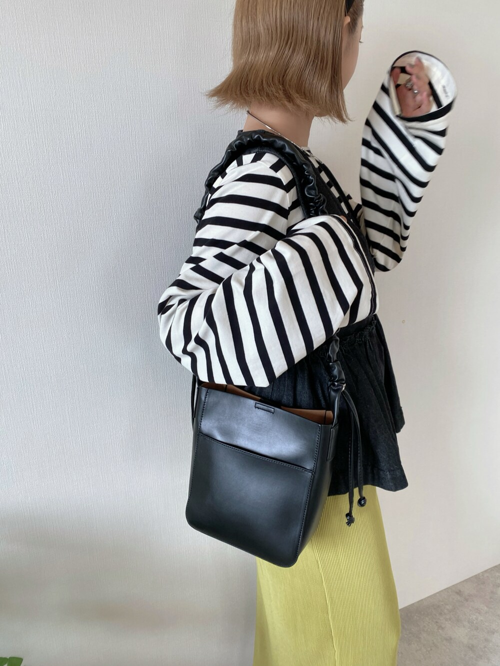 グリーン系のスカート、ブラック系のブーツ、ブラック系のショルダーバッグを着用したレディースの秋コーディネートの3枚目の写真