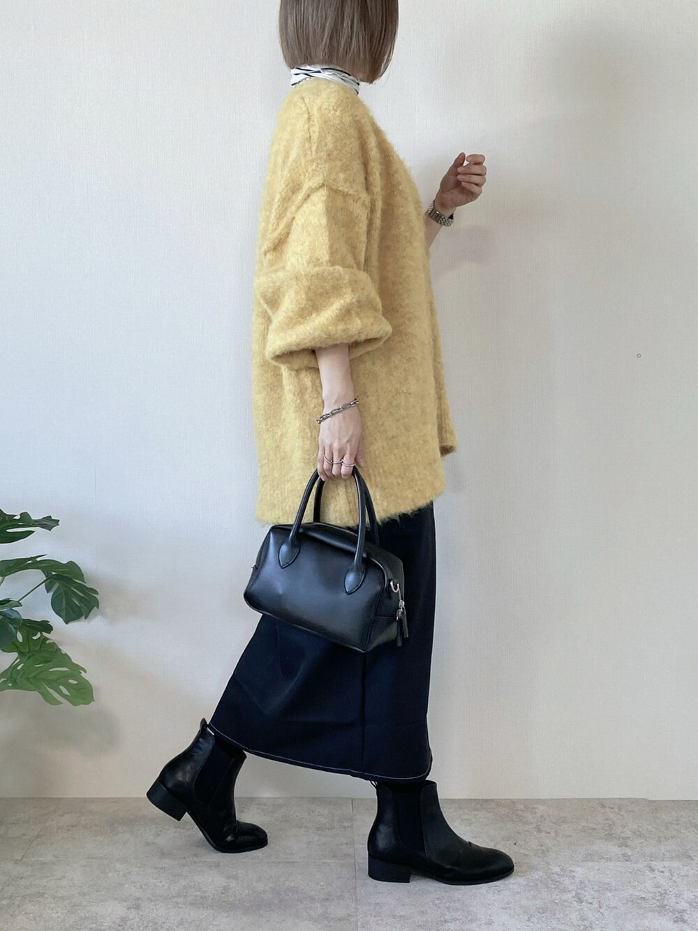 ブラック系のワンピース、ブラック系のブーツ、ブラック系のバッグを着用したレディースの冬コーディネートの3枚目の写真