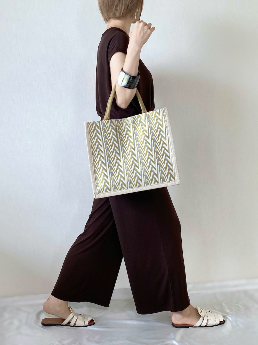 イエロー系のかごバッグ、ブラウン系のその他トップス、ホワイト系のサンダルを着用したレディースの夏コーディネートの2枚目の写真