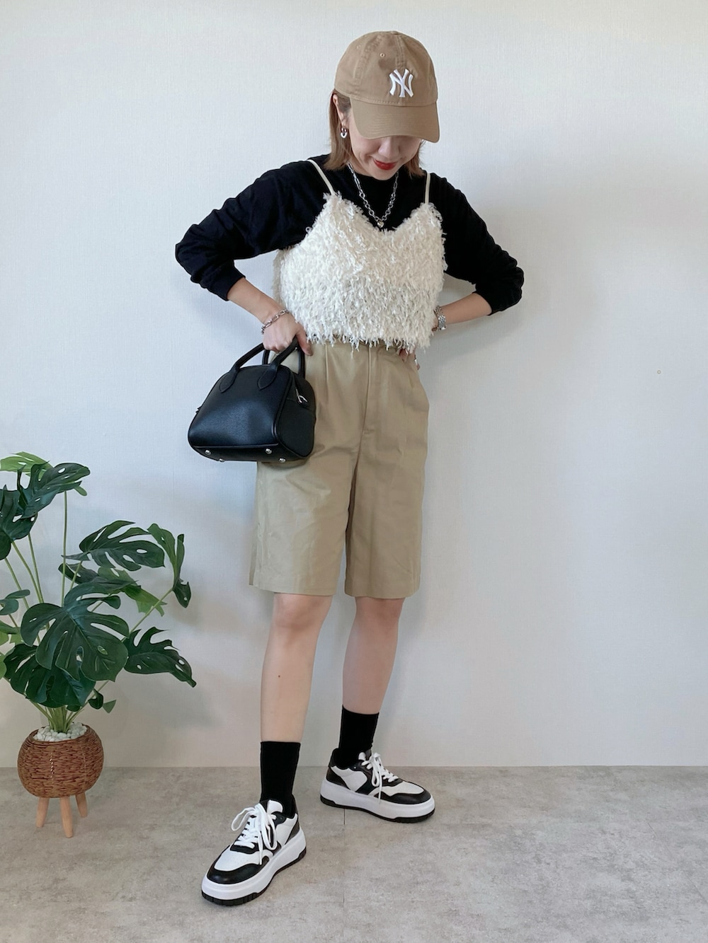 ブラック系のスニーカー、ブラック系のボストンバッグ、ベージュ系のチノパンツを着用したレディースの秋コーディネートの2枚目の写真
