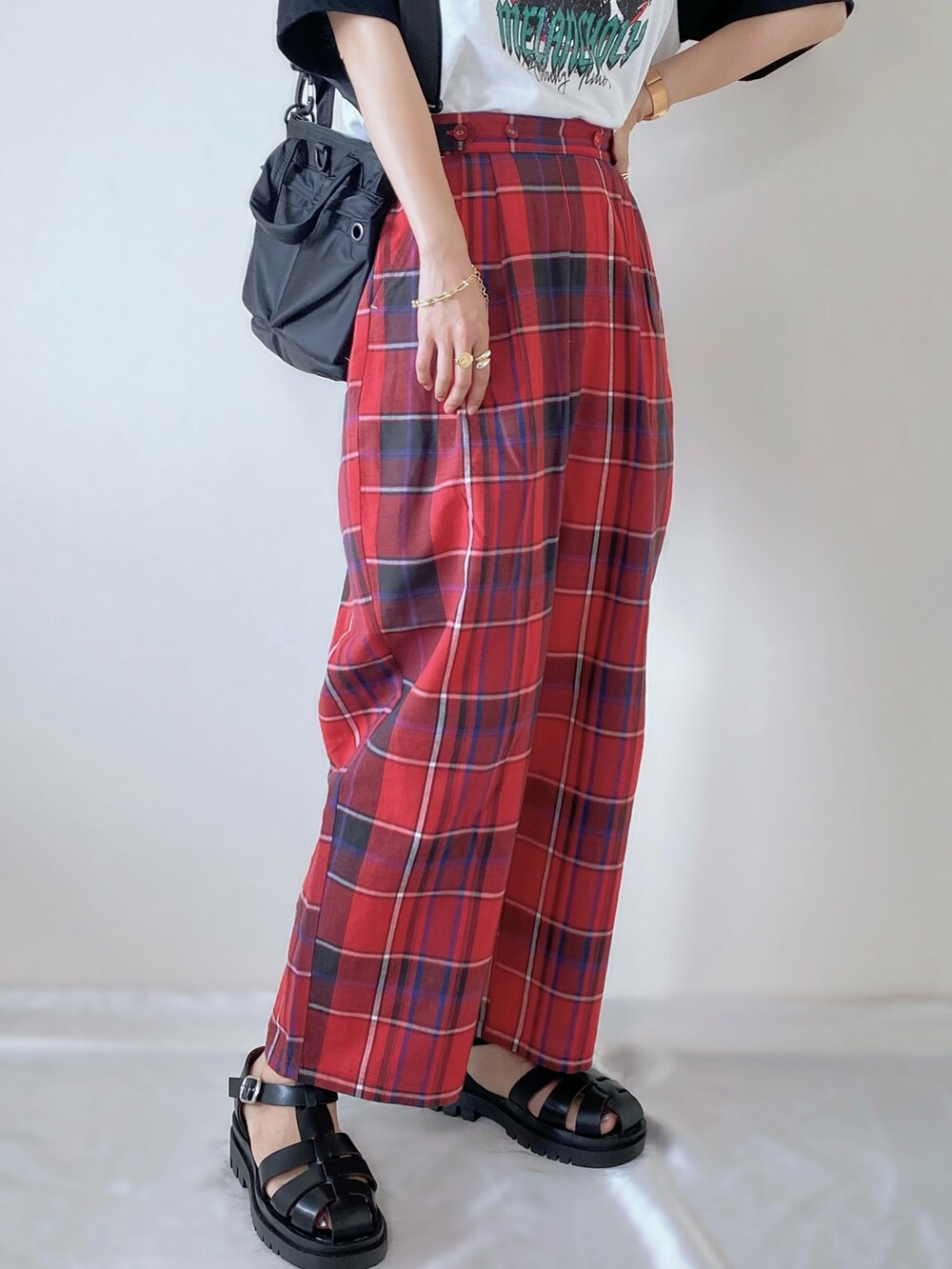 レッド系のパンツ、ブラック系のTシャツ/カットソー、ブラック系のサンダルを着用したレディースの夏コーディネートの3枚目の写真