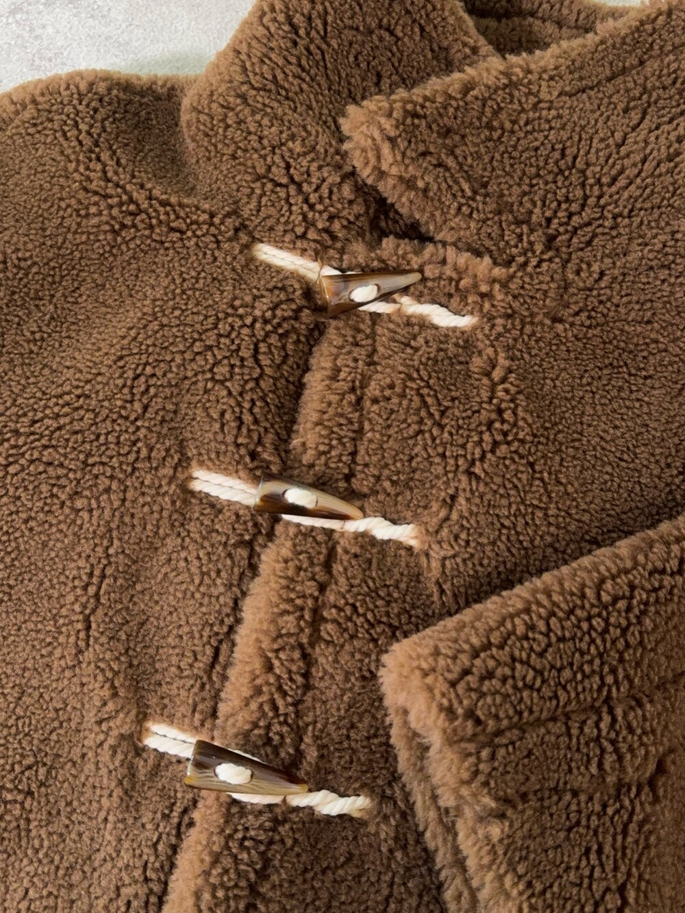 ブラウン系のムートンコート、ブラウン系のハンドバッグ、ブラウン系のブーツを着用したレディースの秋コーディネートの5枚目の写真