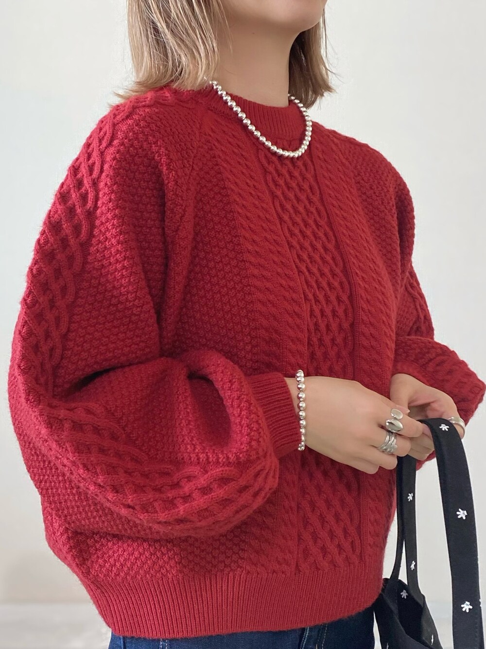 レッド系のニット/セーター、ブラック系のトートバッグ、ブラック系のシューズを着用したレディースの冬コーディネートの3枚目の写真