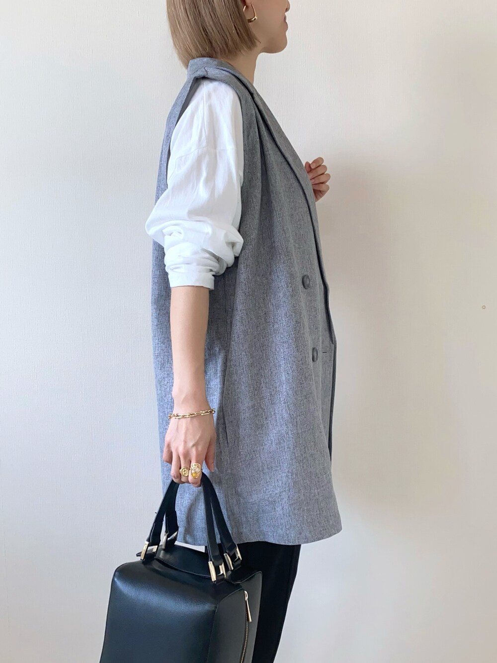 ホワイト系のTシャツ/カットソー、ブラック系のハンドバッグ、ブラック系のパンツを着用したレディースの春コーディネートの5枚目の写真