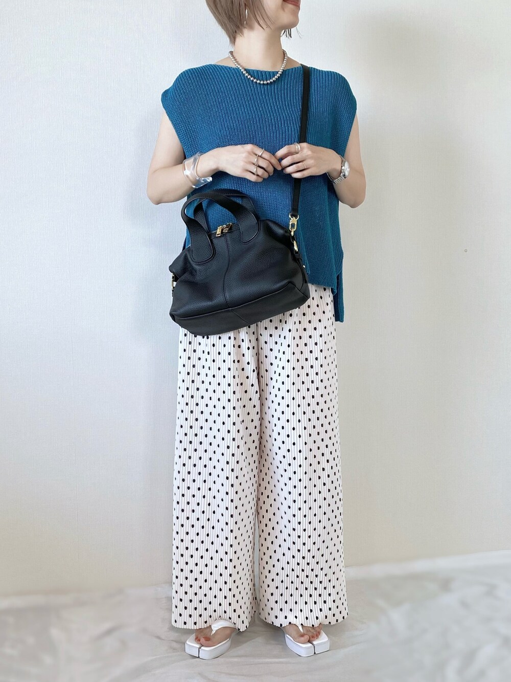 ブラック系のバッグ、ブルー系のベスト、ホワイト系のサンダルを着用したレディースの夏コーディネートの2枚目の写真