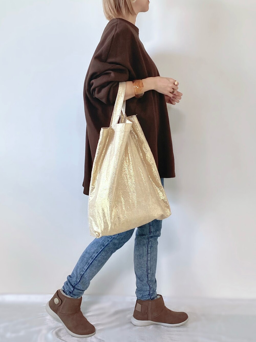 ブラウン系のブーツ、ゴールド系のトートバッグ、ブラウン系のスウェットを着用したレディースの冬コーディネートの2枚目の写真