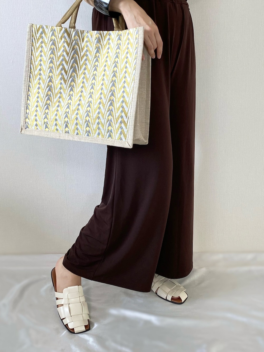 イエロー系のかごバッグ、ブラウン系のその他トップス、ホワイト系のサンダルを着用したレディースの夏コーディネートの4枚目の写真