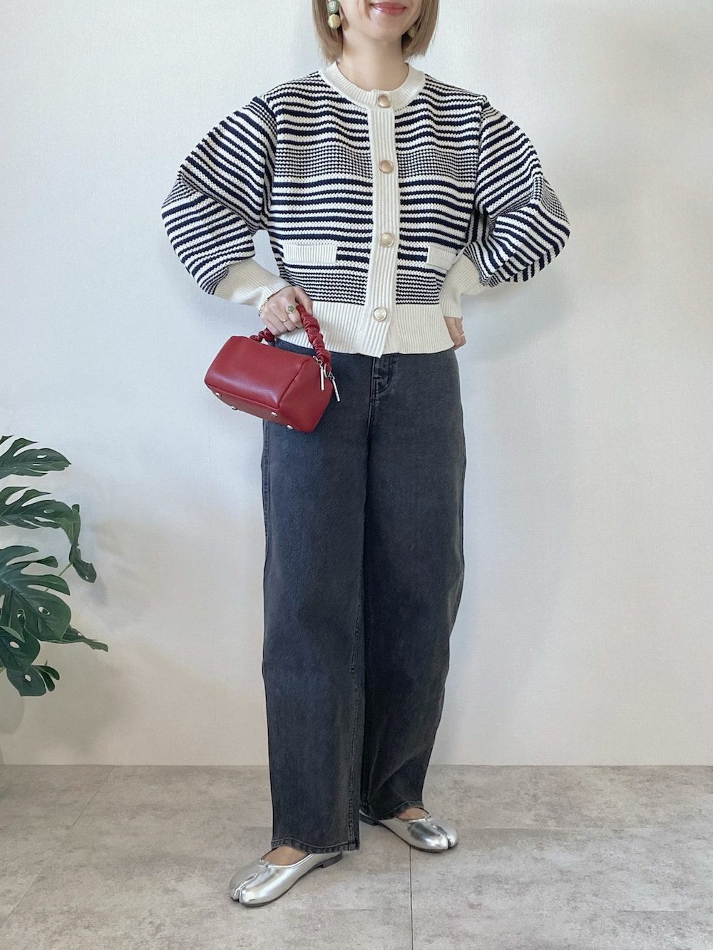 ブラック系のデニムパンツ、レッド系のボストンバッグ、シルバー系のバレエシューズを着用したレディースの冬コーディネートの2枚目の写真