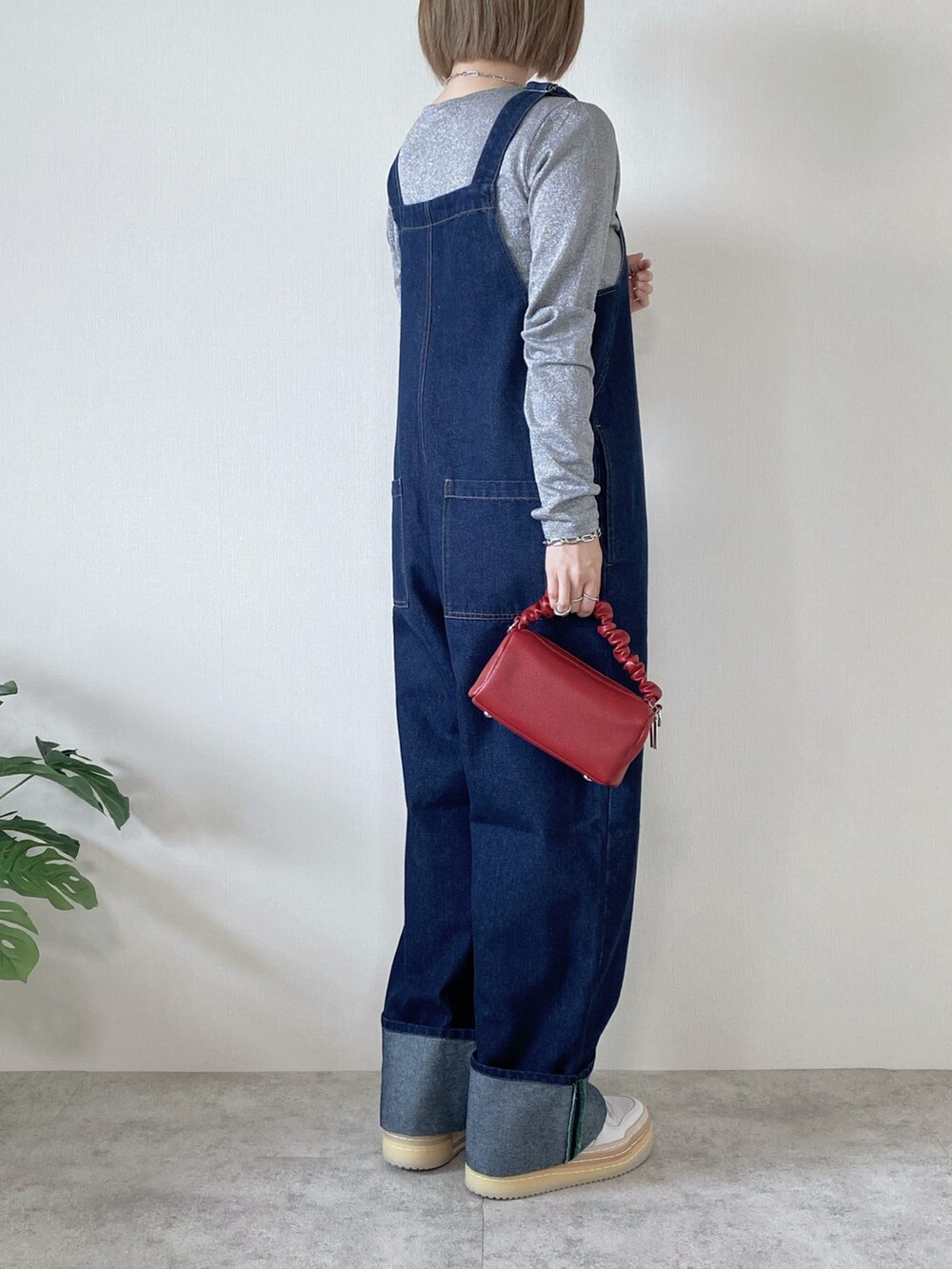 レッド系のボストンバッグ、グレー系のTシャツ/カットソー、ブルー系のサロペット/オーバーオールを着用したレディースの春コーディネートの3枚目の写真