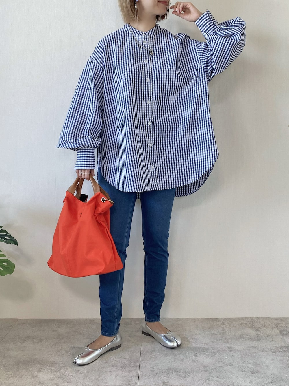 オレンジ系のトートバッグ、シルバー系のバレエシューズ、ブルー系のシャツ/ブラウスを着用したレディースの冬コーディネートの2枚目の写真