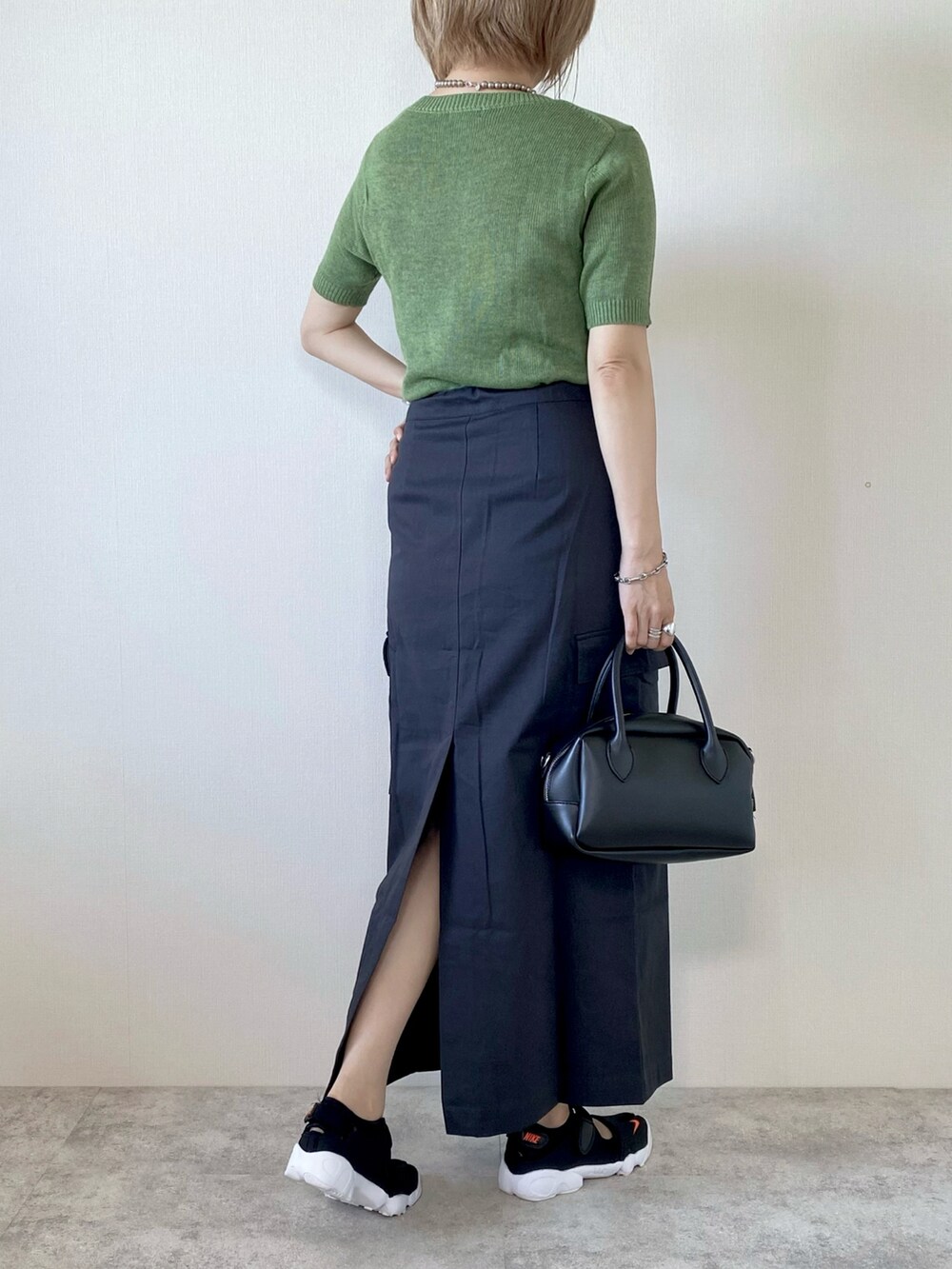 ブルー系のベスト、グリーン系のニット/セーター、グレー系のスカートを着用したレディースの秋コーディネートの4枚目の写真