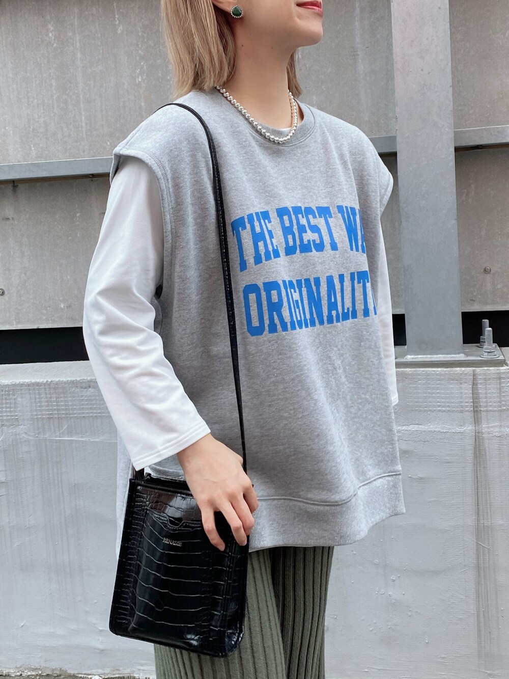 グレー系のベスト、ホワイト系のTシャツ/カットソー、ブラック系のバッグを着用したレディースの冬コーディネートの3枚目の写真