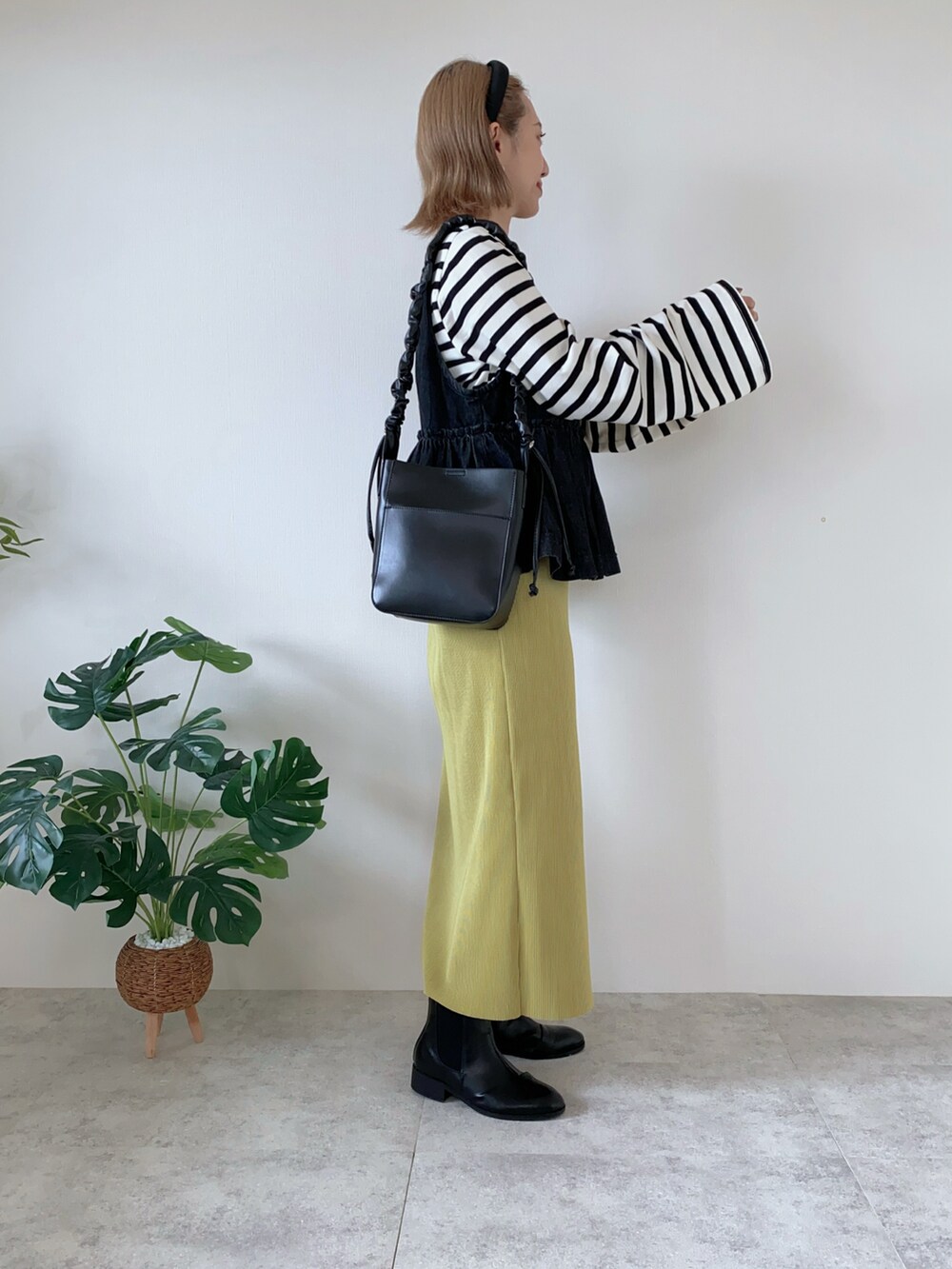 グリーン系のスカート、ブラック系のブーツ、ブラック系のショルダーバッグを着用したレディースの秋コーディネートの2枚目の写真