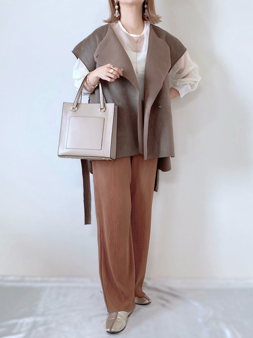 ベージュ系のベスト、ホワイト系のシャツ/ブラウス、ベージュ系のパンツを着用したレディースの秋コーディネートの2枚目の写真