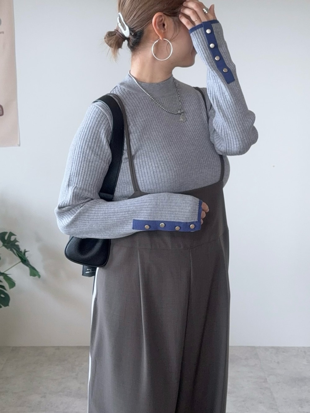 グレー系のニット/セーター、グレー系のサロペット/オーバーオール、シルバー系のパンプスを着用したレディースの秋コーディネートの2枚目の写真