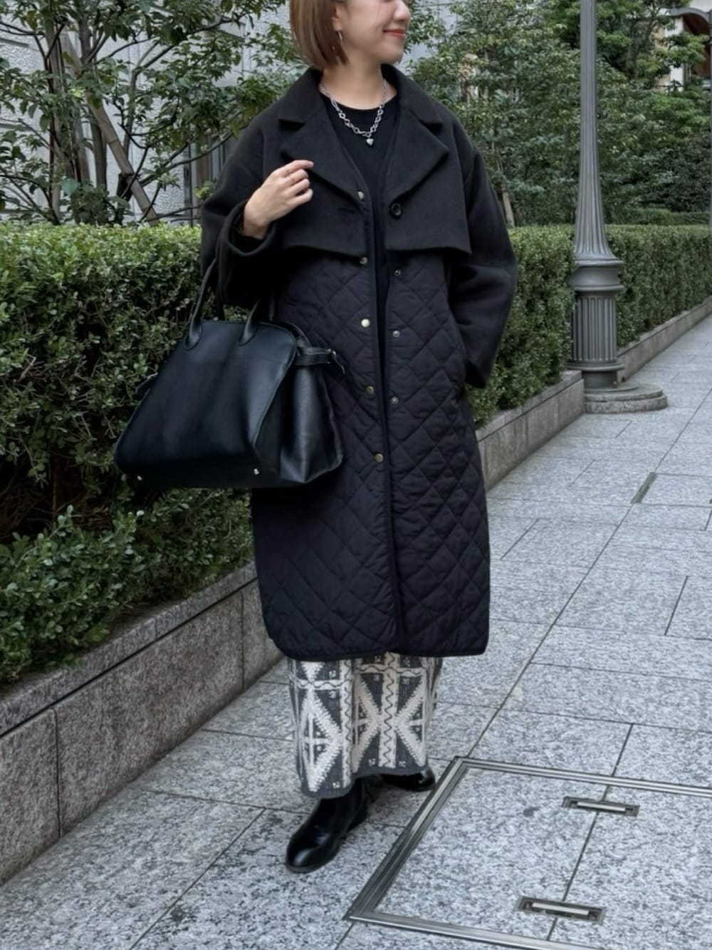 ブラック系のボストンバッグ、グレー系のスカート、ブラック系のブーツを着用したレディースの冬コーディネートの2枚目の写真