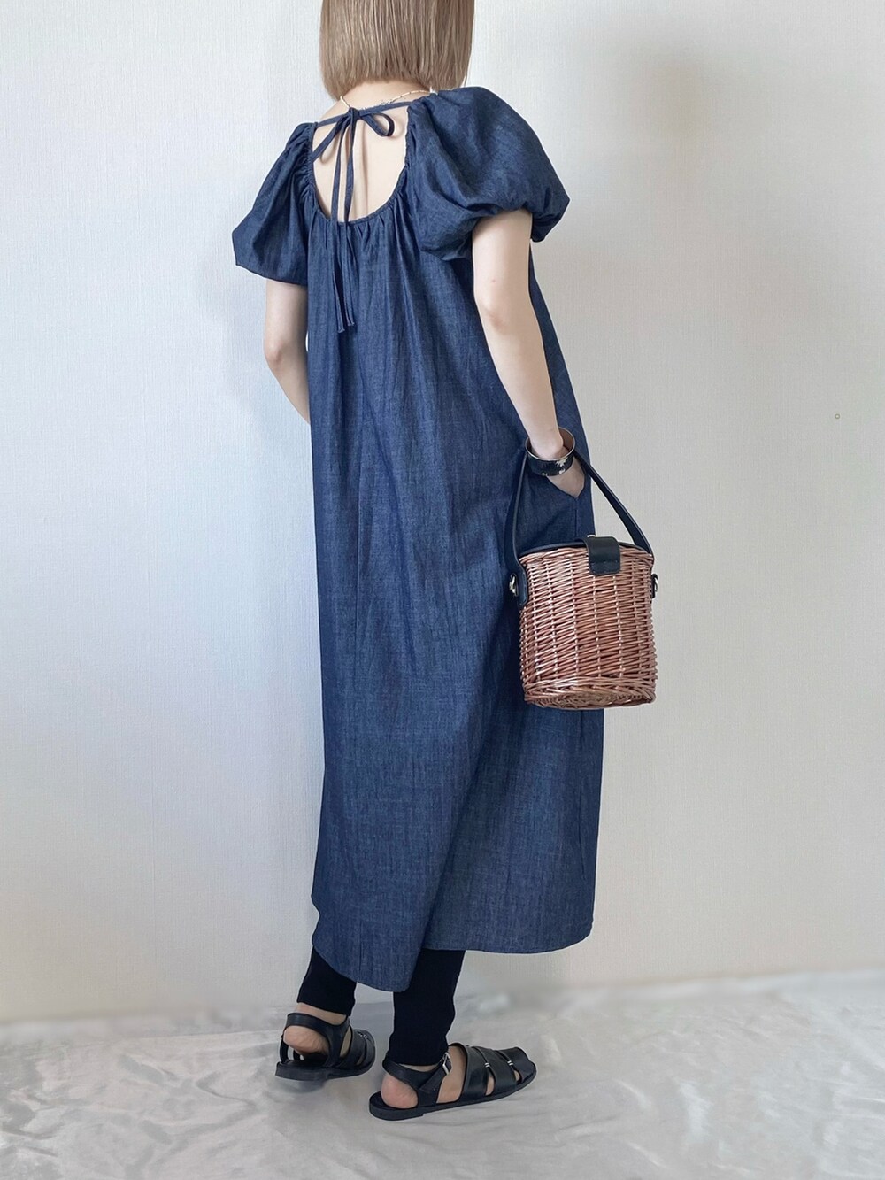 ブラック系のバッグ、ブルー系のワンピース、ブラック系のサンダルを着用したレディースの春コーディネートの2枚目の写真