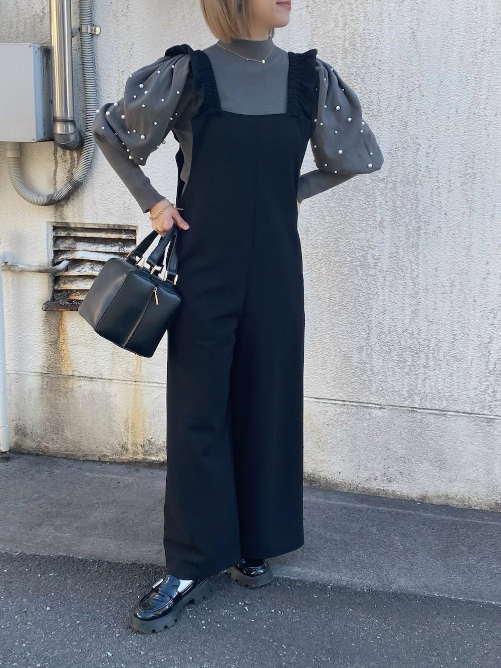 グレー系のニット/セーター、ブラック系のハンドバッグ、ブラック系のローファーを着用したレディースの冬コーディネートの2枚目の写真