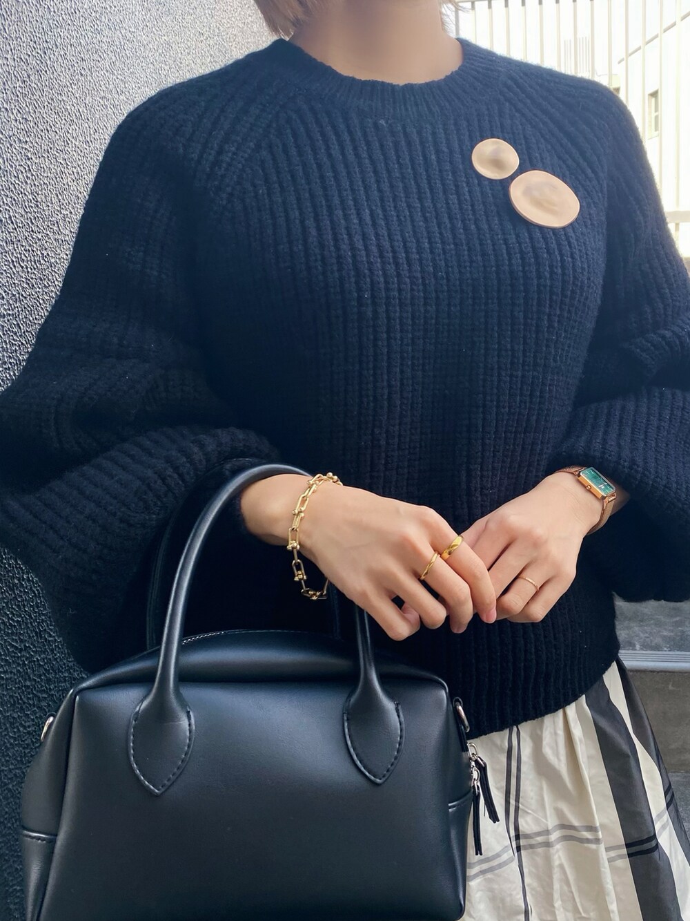 ブラック系のニット/セーター、ブラック系のバッグ、ホワイト系のスカートを着用したレディースの冬コーディネートの2枚目の写真