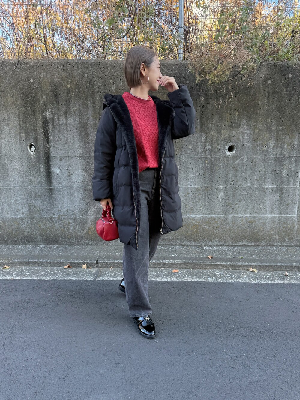 ブラック系のダウンジャケット/コート、レッド系のニット/セーター、ブラック系のデニムパンツを着用したレディースの冬コーディネートの2枚目の写真