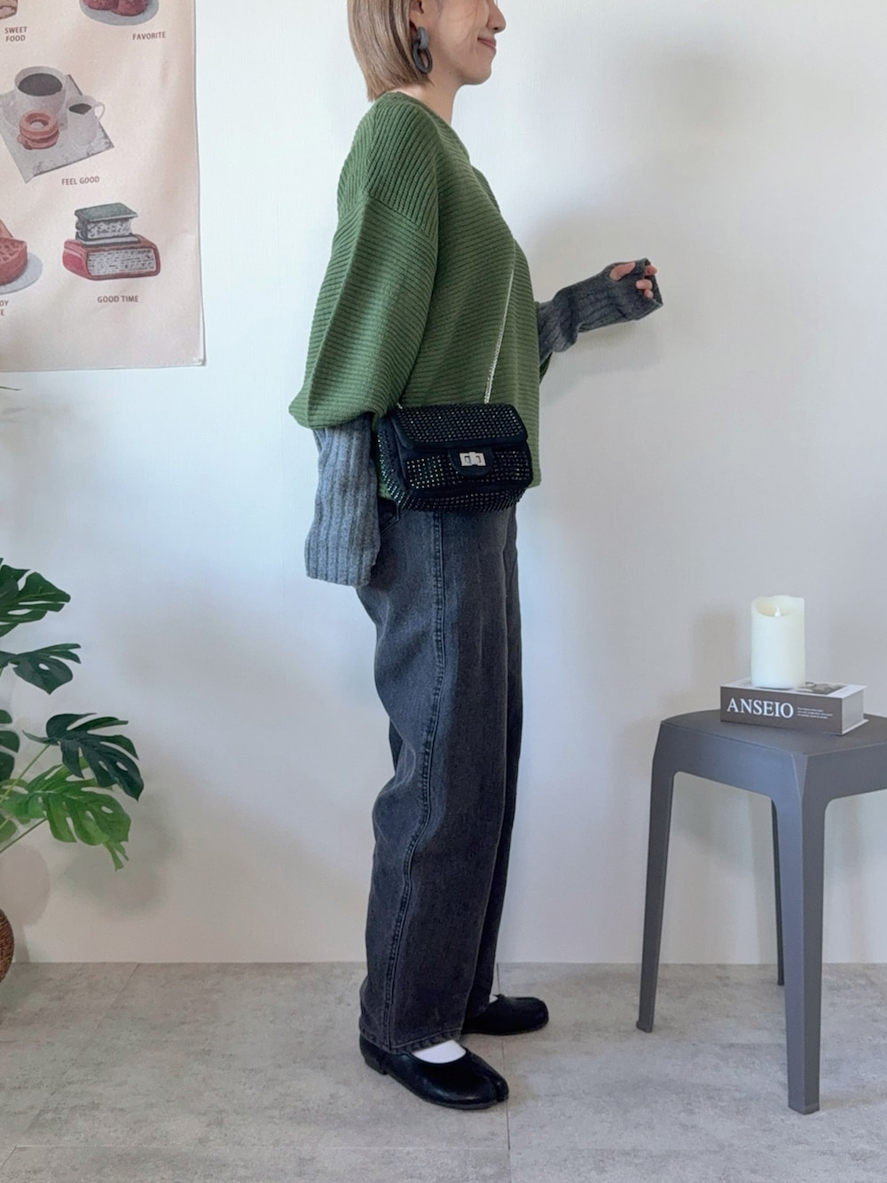 グリーン系のニット/セーター、ブラック系のデニムパンツ、ブラック系のクラッチバッグを着用したレディースの秋コーディネートの3枚目の写真