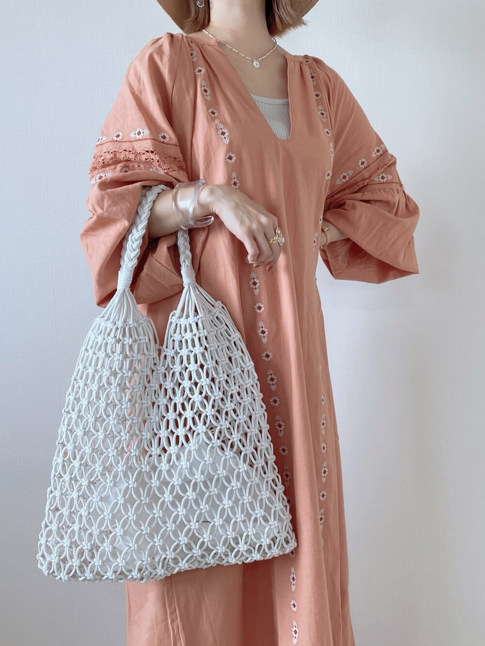 ホワイト系のかごバッグ、ピンク系のワンピース、ベージュ系のサンダルを着用したレディースの春コーディネートの3枚目の写真