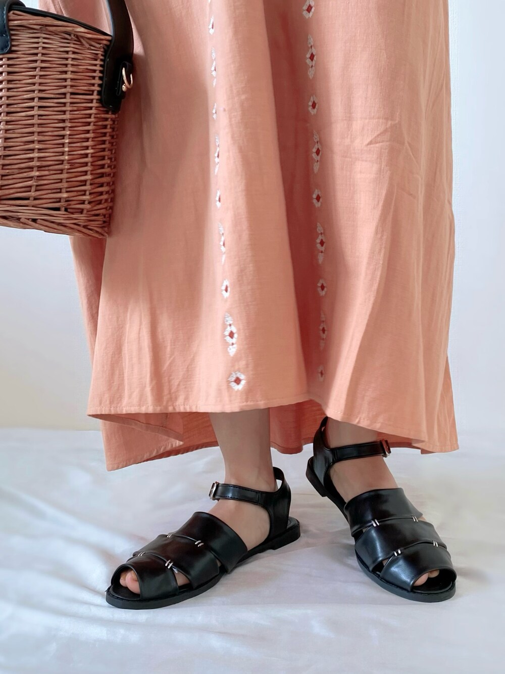 ブラック系のバッグ、ピンク系のワンピース、ブラック系のサンダルを着用したレディースの春コーディネートの3枚目の写真