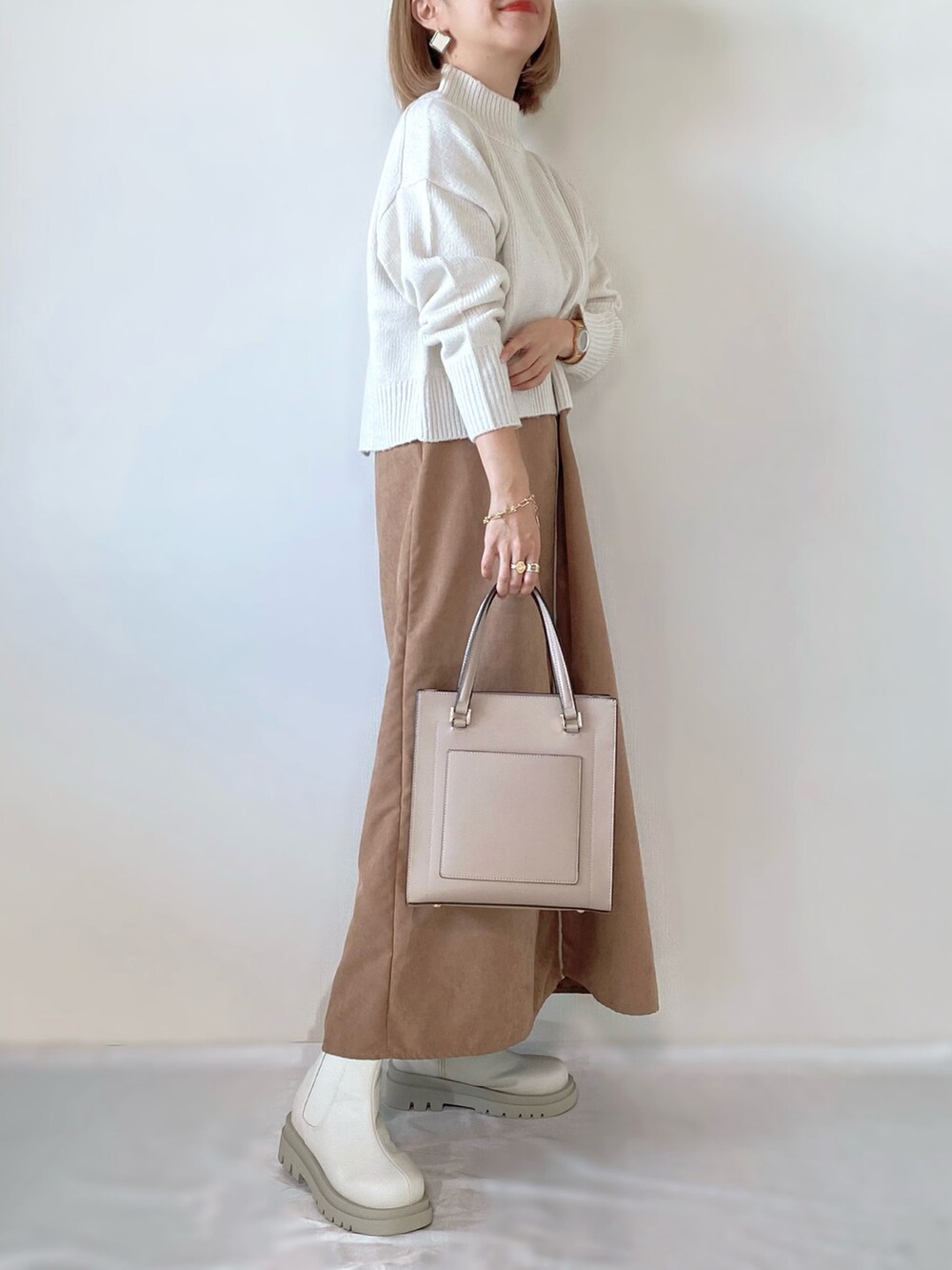 ホワイト系のニット/セーター、ブラウン系のワンピース、ホワイト系のブーツを着用したレディースの秋コーディネートの2枚目の写真