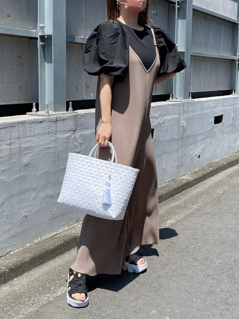 ブラック系のトップス、ホワイト系のかごバッグ、ブラック系のサンダルを着用したレディースの夏コーディネートの3枚目の写真