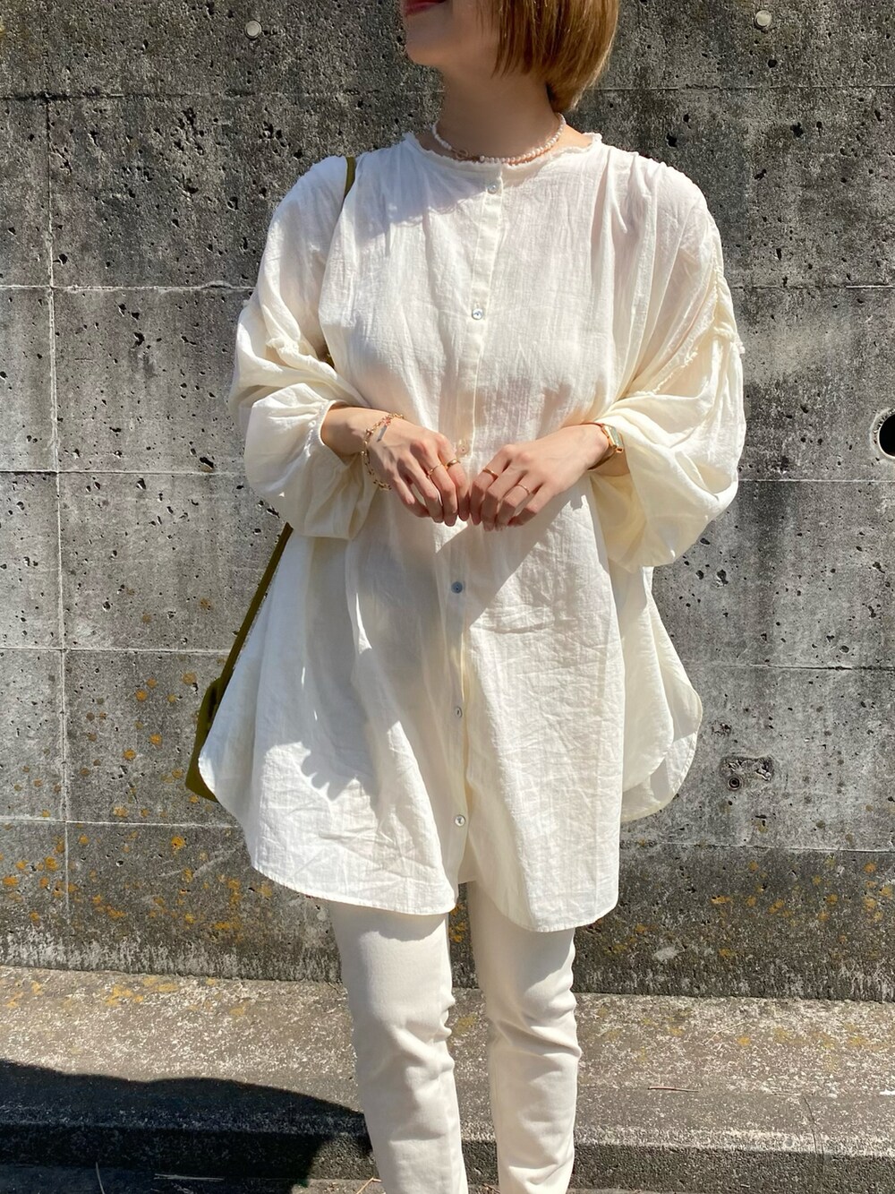 ブラウン系のパンプス、グリーン系のボストンバッグ、ホワイト系のシャツ/ブラウスを着用したレディースの春コーディネートの2枚目の写真