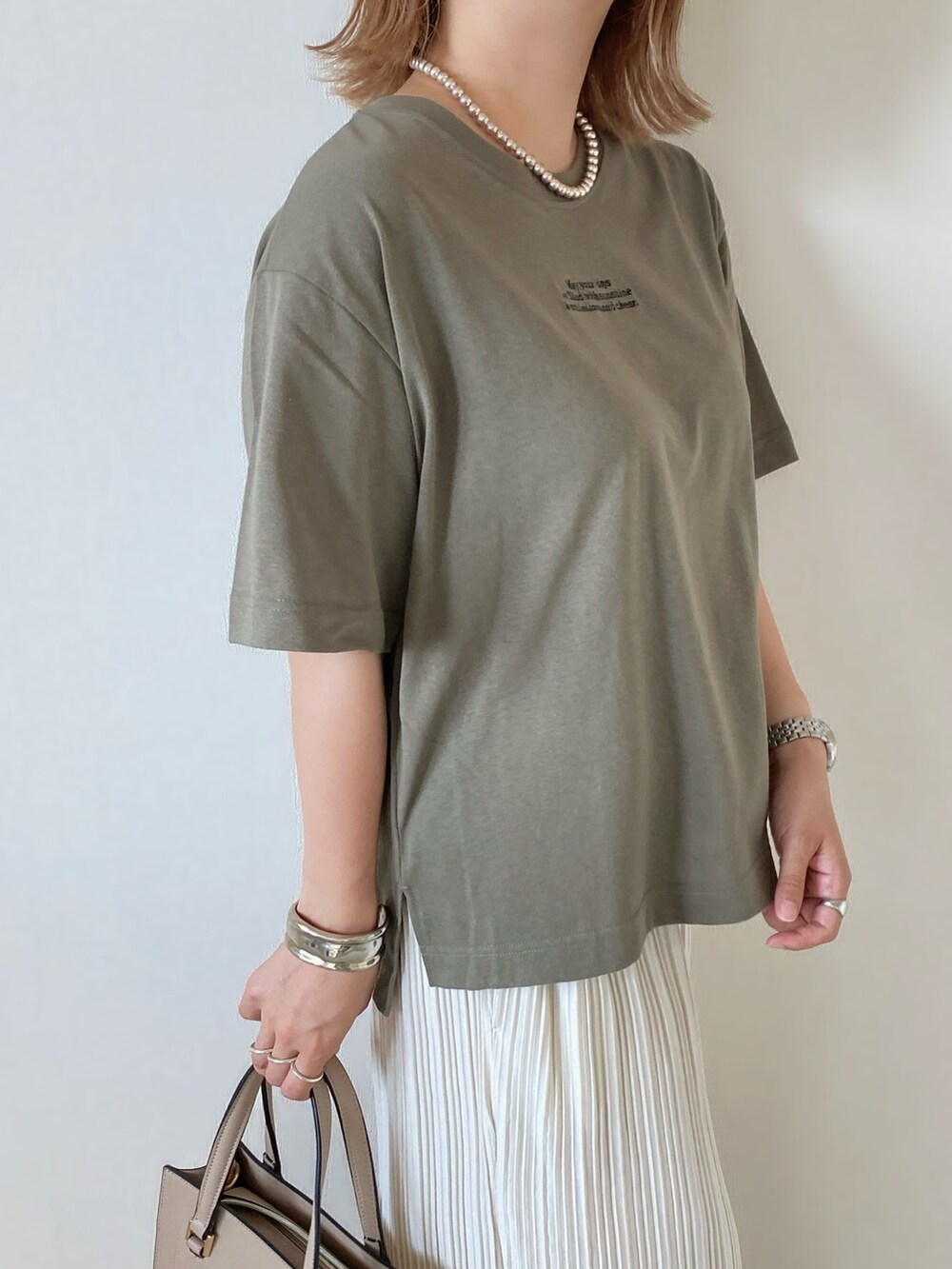 グリーン系のTシャツ/カットソー、ベージュ系のバッグ、ホワイト系のパンツを着用したレディースの夏コーディネートの4枚目の写真