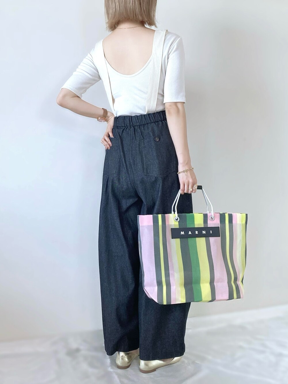 グリーン系のトートバッグ、ブラック系のデニムパンツ、ホワイト系のTシャツ/カットソーを着用したレディースの春コーディネートの2枚目の写真