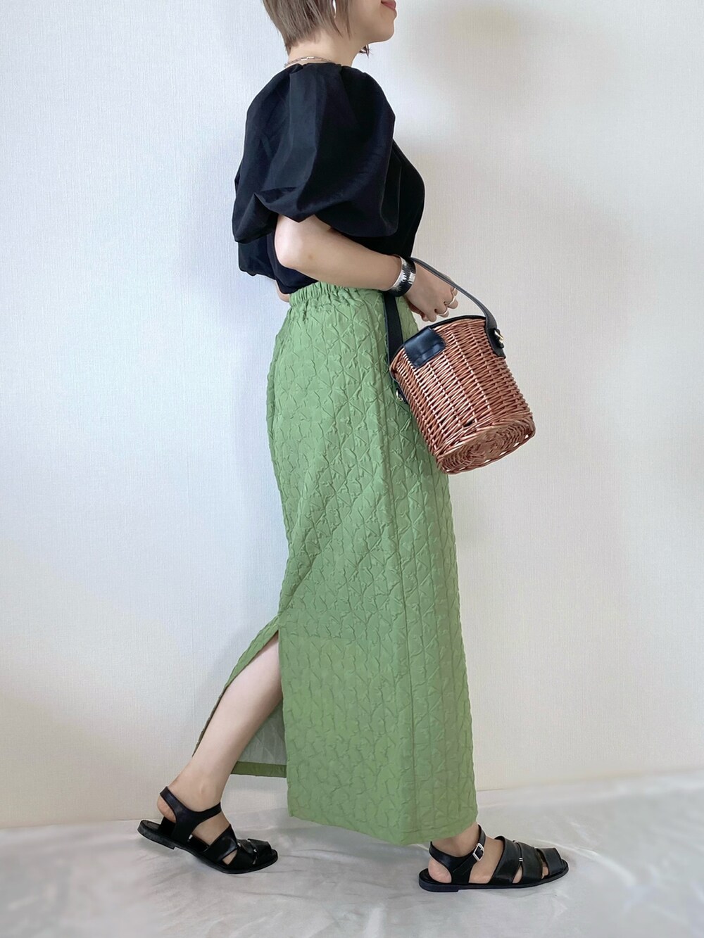 グリーン系のスカート、ブラック系のトップス、ブラック系のバッグを着用したレディースの夏コーディネートの2枚目の写真